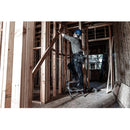 Работник на стълба в строителен обект, използващ стълба за работа с дървени конструкции.