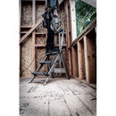 Работник на стълба, използващ електрически инструмент в строителен обект.