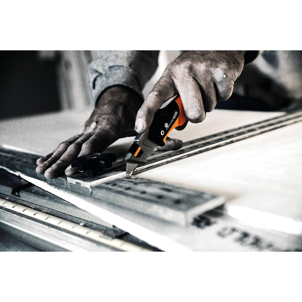 Сгъваем макетен нож Fiskars Pro CarbonMax™ 1027224 в употреба при рязане на материали, здрава стоманена конструкция и двойно заключване