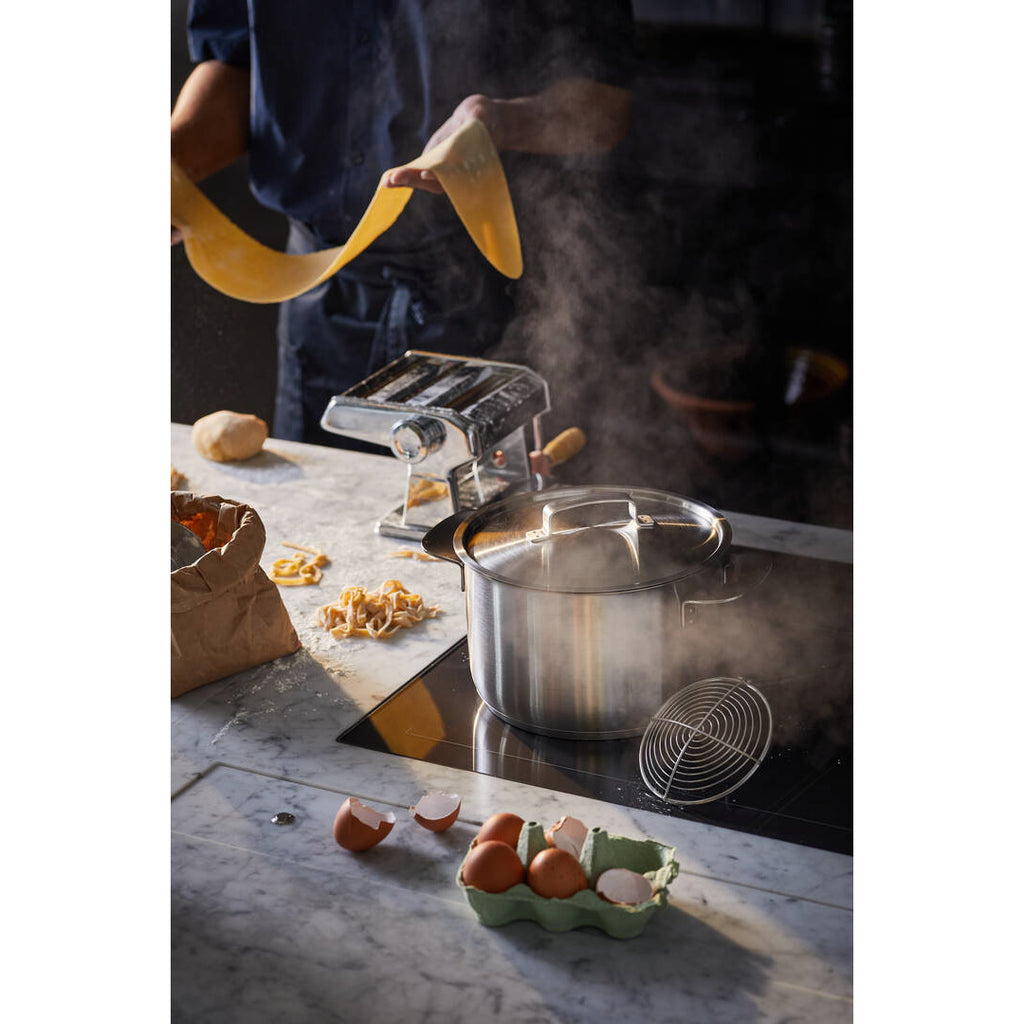 Тенджера Fiskars All Steel, 5.0 l върху индукционен котлон с капак, пара и пресни яйца около нея