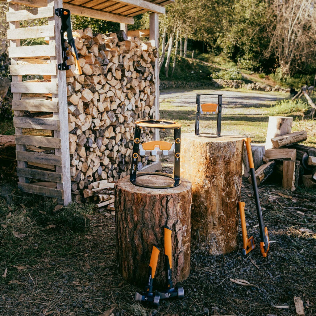 Строителен чук Fiskars IsoCore™ размер M насядан върху дървен труп до цепач и дърва за огрев