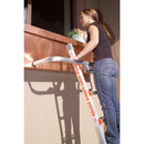 Жена използва стенен дистанционер Little Giant® WingSpan™, като стои на стълба до прозорец.