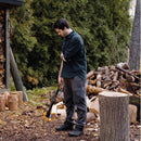 Мъж с брадва за цепене на дърва Fiskars X27 в гора, готов за работа с трупи.