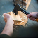 Човек с брадва Fiskars X7, който разцепва дървен блок на подпалки.