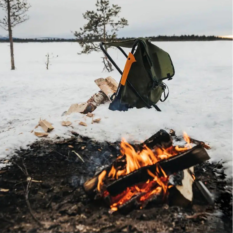 Брадва Fiskars X7 XS до лагерен огън на снежна земя с туристическа раница.