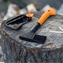 Брадва Fiskars X7 XS на дънер, с предпазител до нея, идеална за къмпинг и туризъм.
