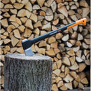 Брадва за цепене на дърва Fiskars X21, поставена на дървено трупче с фон от нарязани дърва.