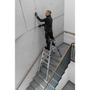 Професионалист използва алуминиева телескопична стълба Krause STABILO за работа на тясно стълбище.