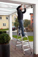 Мъж използва двустранна алуминиева стълба KRAUSE DOPPLO 2x6 за ремонтни дейности на веранда.