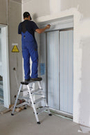 Работник на стълба KRAUSE TREPPO боядисва стена на височина в интериорна среда.