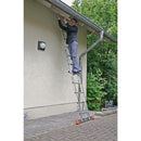 Мъж, използващ двойна алуминиева стълба KRAUSE TRIMATIC 2x8 за работа на покрива.