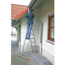 Човек, стоящ на алюминиева стълба KRAUSE TRIMATIC, почистваща канал за вода на покрив на къща.