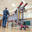 Работник пренася телескопична стълба с колела в спортен салон, демонстрира удобство и мобилност.