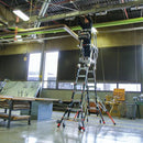 Работник на телескопична стълба от фибростъкло с предпазен кош в промишлено помещение.