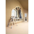 Човек, който боядисва прозорци, стоящ на стълбище с Telescoping Plank™ за работа на височина.