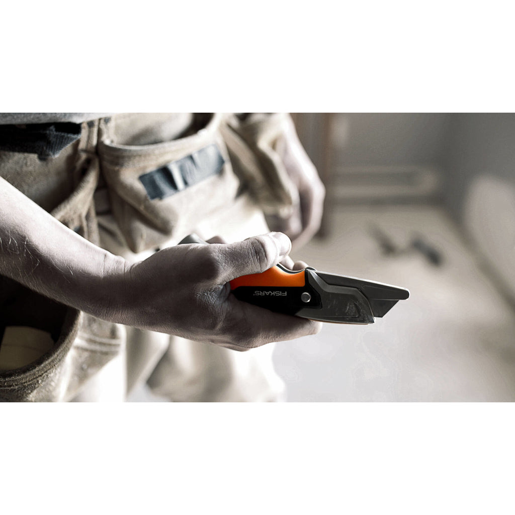 Макетен нож с фиксирано острие Fiskars Pro CarbonMax™ в ръка на майстор, сгъваем предпазител и резервно дълготрайно острие