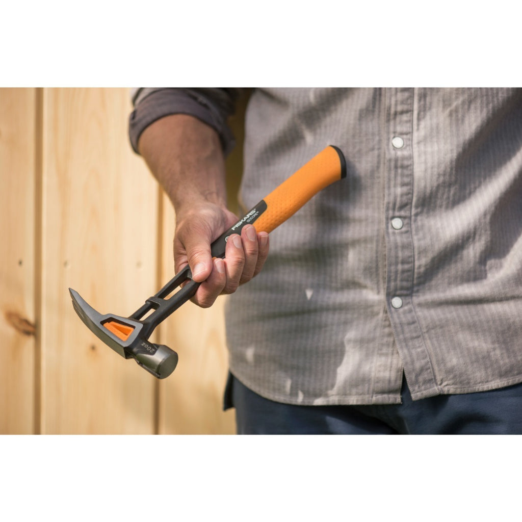 Универсален чук Fiskars IsoCore™ размер L в ръка на майстор, оранжево-черна дръжка и патентована система за намаляване на вибрациите