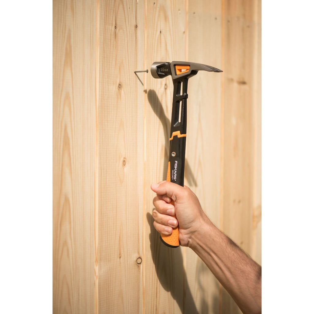 Универсален чук Fiskars IsoCore™ размер L в употреба за прибиване на пирон в дървена ламперия