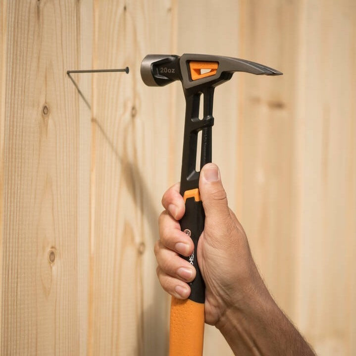 Универсален чук Fiskars IsoCore™ размер L в ръка удря пирон, патентована система IsoCore за намаляване на вибрациите