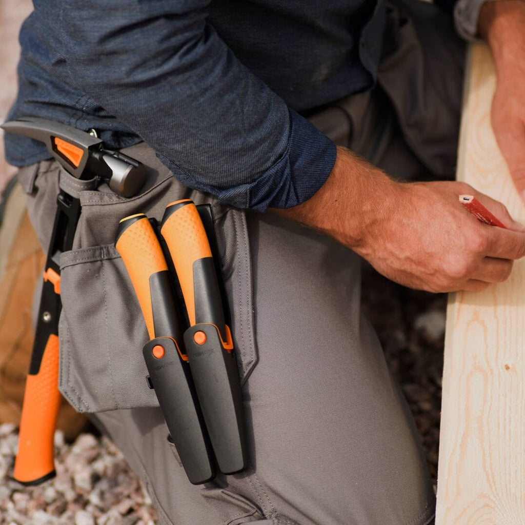 Универсален чук Fiskars IsoCore™ размер L в кобур на работник, готов за дърводелски и монтажни задачи
