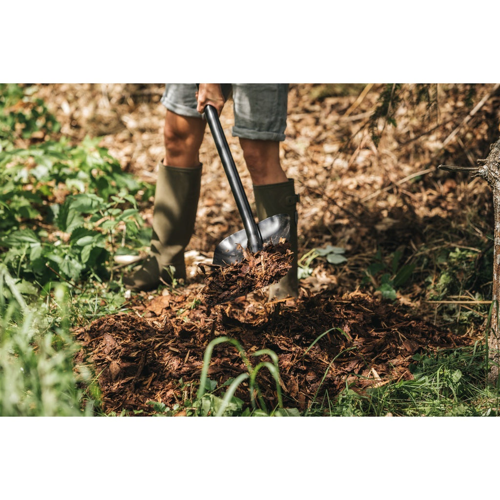 Лопата за насипни материали Fiskars Solid™ в действие при преместване на мулч с дълга стоманена дръжка и D-образна ръкохватка
