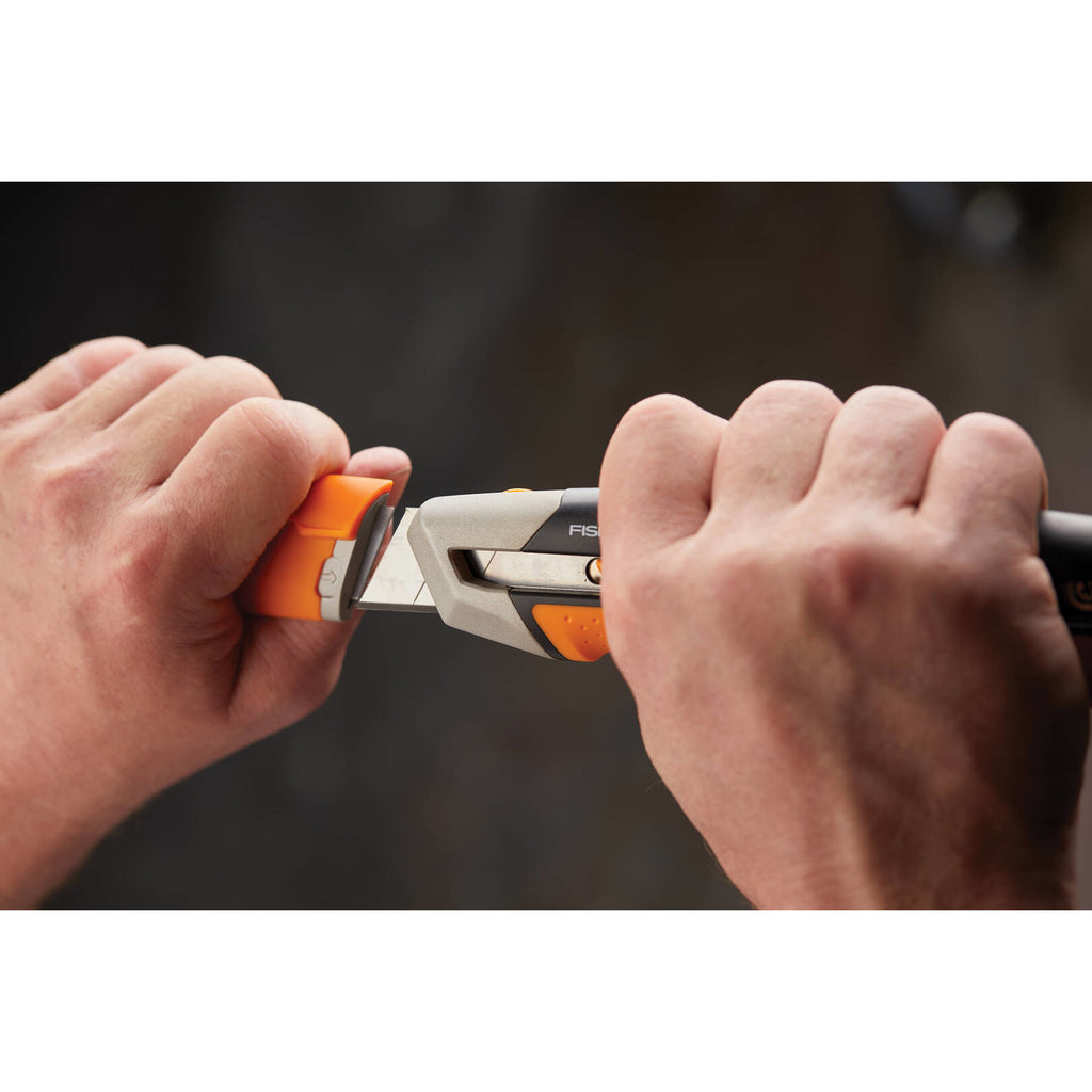 Универсален макетен нож CarbonMax™ 25 mm в ръце, демонстриране на лесна и бърза смяна на 25 мм острие