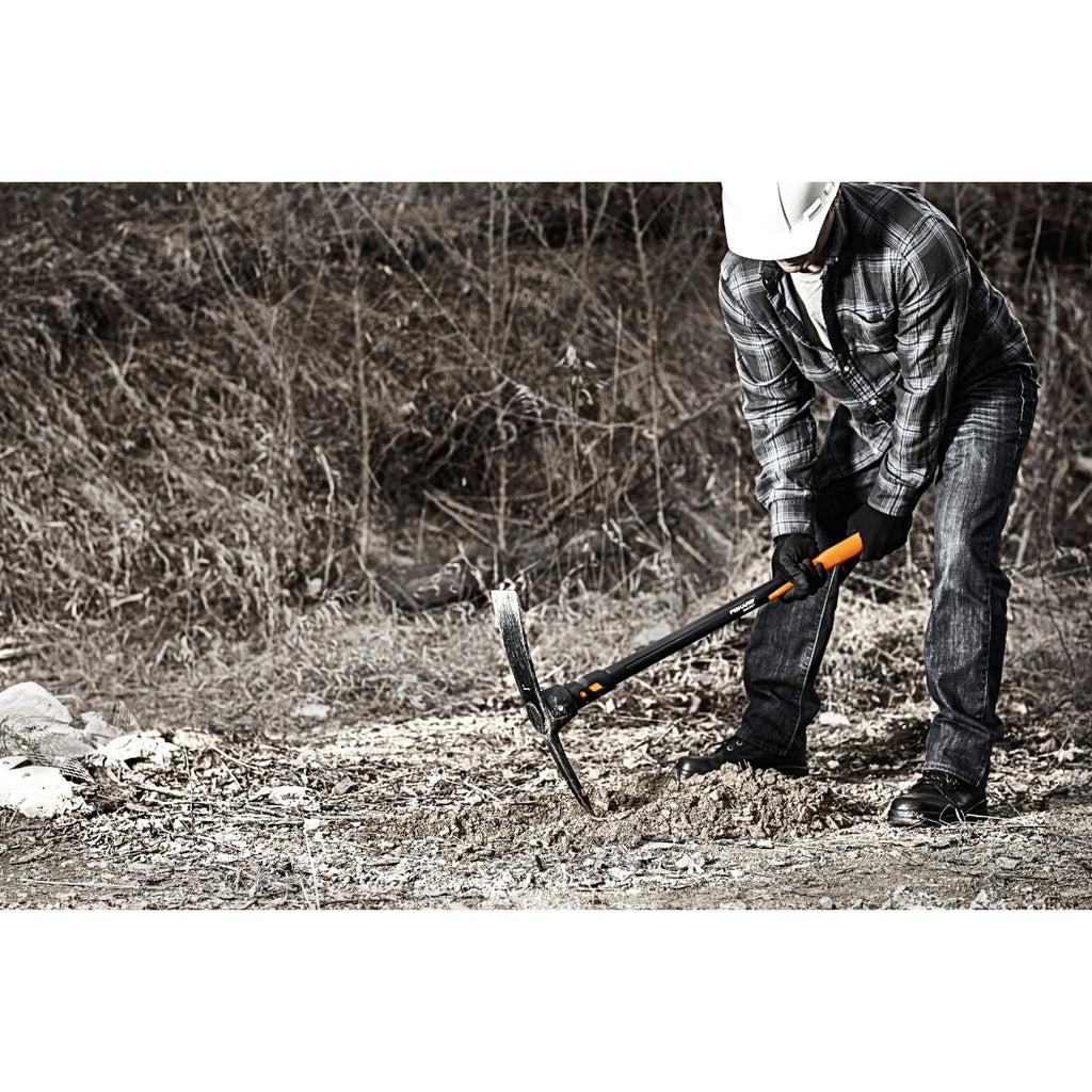 Alt Tag: Кирка Fiskars Pro IsoCore™, размер L – работник кове в камениста почва с кирка Fiskars Pro IsoCore™ за по-ниски вибрации