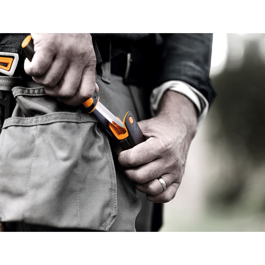Универсален нож с вградено точило в канията Fiskars в калъф, показан при работа с лесно достъпно вградено точило