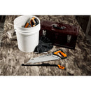 Трион Fiskars PRO PowerTooth (38 см, 9 TPI) с тройно заточено острие и оранжева дръжка върху работна настилка до кофа и инструментална кутия