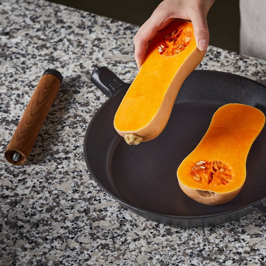 Чугунен тиган Fiskars Norden 26 см с емайлирана повърхност Thermium™, показан с нарязан тиквен плод за готвене