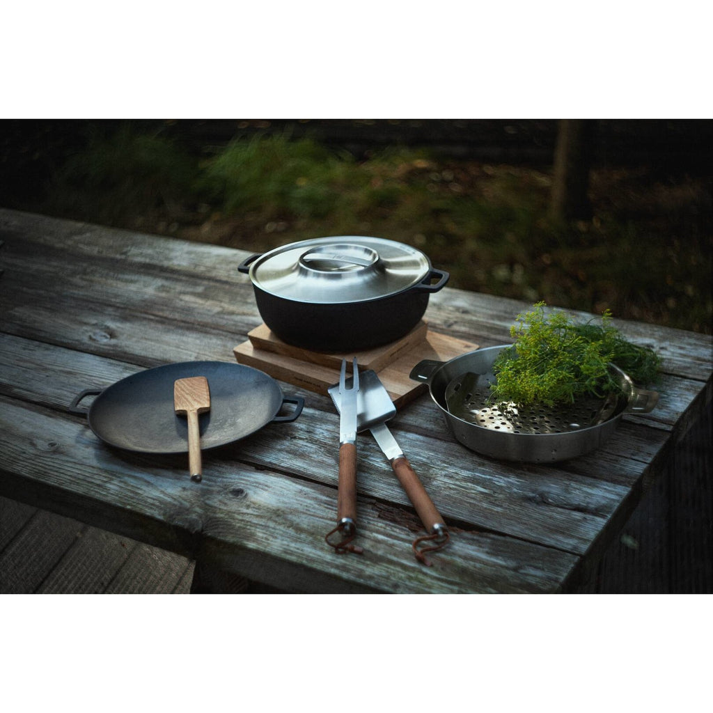 Чугунен гювеч Norden Grill Chef с капак, 30 см. на маса сред прибори за барбекю и пресни подправки