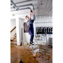 Работник на стълба KRAUSE TREPPO, монтиране на тръби в помещение с метални тръби и инструменти.