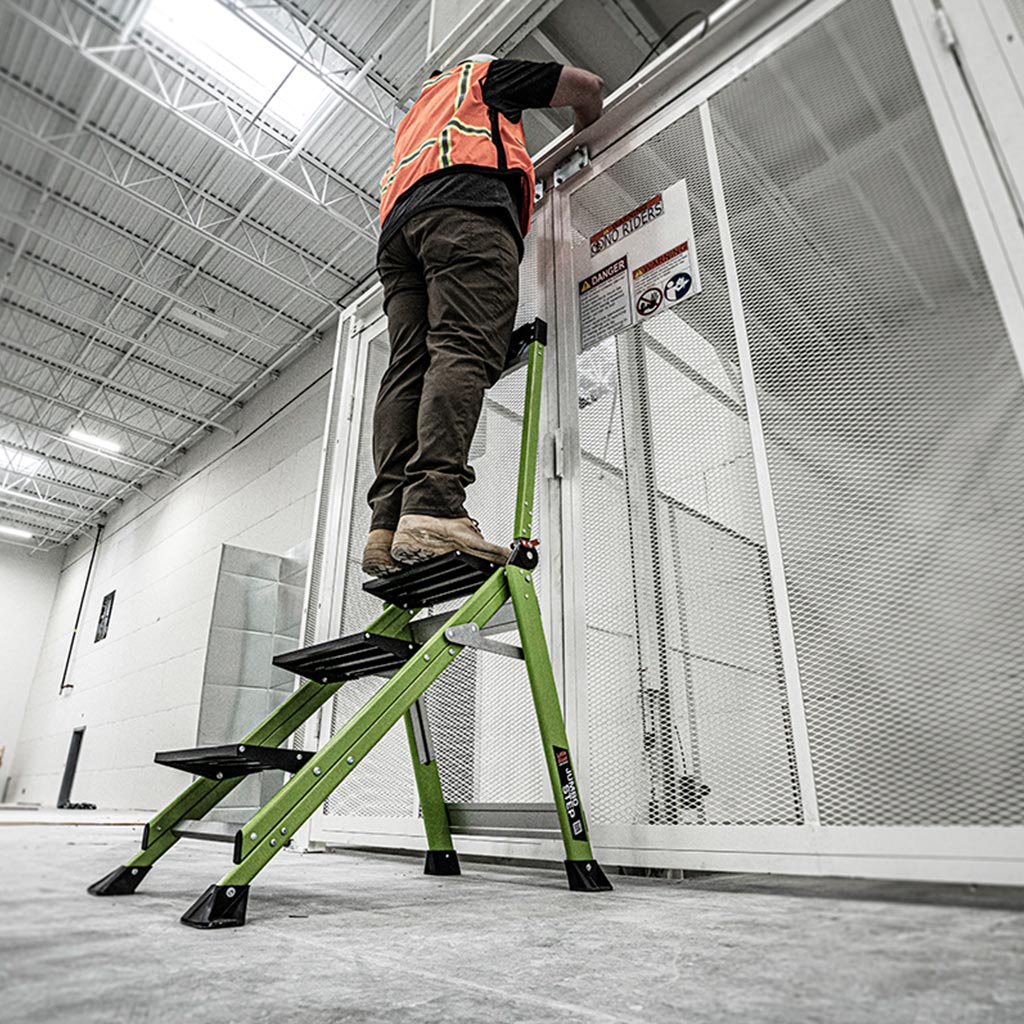 Работник на стълба от фибростъкло Little Giant® Jumbo Step, монтаж на врата в търговски обект.