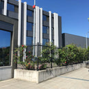 Оградна система ASPEN около растителност с модерна сграда на фона. Издръжлива, антикорозионна технология за безпроблемна поддръжка.