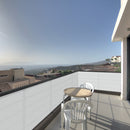 Тераса с изглед към планината, обзаведена с маса и пластмасови столове.