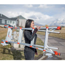 Жена носи алуминиева стълба Leveler Малкия гигант® на открито, удобна за използване по неравни повърхности.