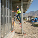 Телескопична алуминиева стълба Leveler Малкия гигант® в употреба на строителен обект, показана върху неравна повърхност.