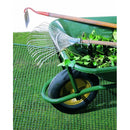 Зелена градинска количка с метален гребло и лопата, натоварена с зеленина, разположена на мрежа.