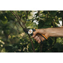 Демонстрация на лозарска ножица Fiskars с пресрещащи се остриета в ръка, идеална за подрязване на клони.