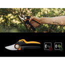 Лозарска ножица PowerGear M P921 в ръка сред зеленина, показваща остриета и ергономична дръжка.