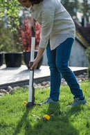 Жена използва изкоренител за плевели Light за отстраняване на глухарчета от тревната площ.