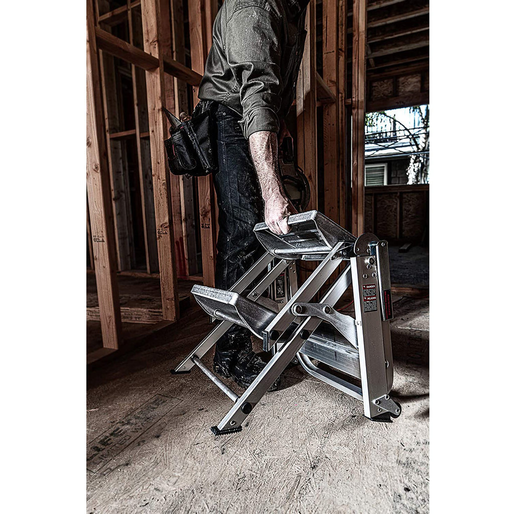 Човек държи стълба SAFETY STEP МАЛКИЯ ГИГАНТ® в строителен обект, демонстрирайки удобството на стълбата.