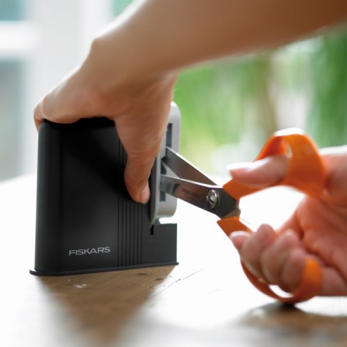 Точило за ножици FISKARS с търкалящ се керамичен камък, удобно за използване с две ръце.