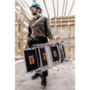 Мъж с каска, носещ стълба Little Giant в строителен обект. Стълбата е сгъваема и практична.