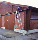 Работник на двураменна стълба KRAUSE CORDA, извършващ домашна работа на фасадата на сграда.