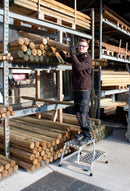 Работник на стълбичка KRAUSE STABILO, който достига дървени материали в склад.