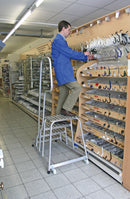 Мъж на стълба с 4 стъпала, работещ в магазин. Стабилна конструкция за безопасна работа.