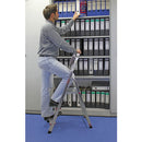 Мъж, стоящ на алуминиева стълба Krause Corda, организира папки на стена с документи.