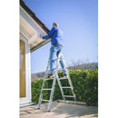 Мъж с немско мобилно скеле KRAUSE CORDA, извършва работа по покрива на къща, демонстрирайки компактна и лесна употреба.