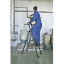 Човек на алуминиева стълба KRAUSE SePro S в индустриална среда, работещ по тръбопровод.